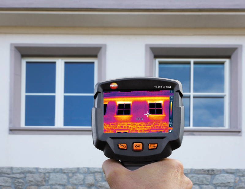 a man hand holding testo 872s thermal imaging camera and scanning the external  window areas of a building