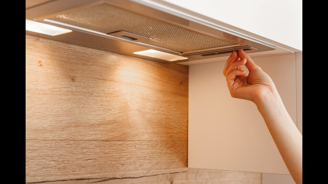 Mechanical ventilation woman's hand turning on embedded cooker hood in white